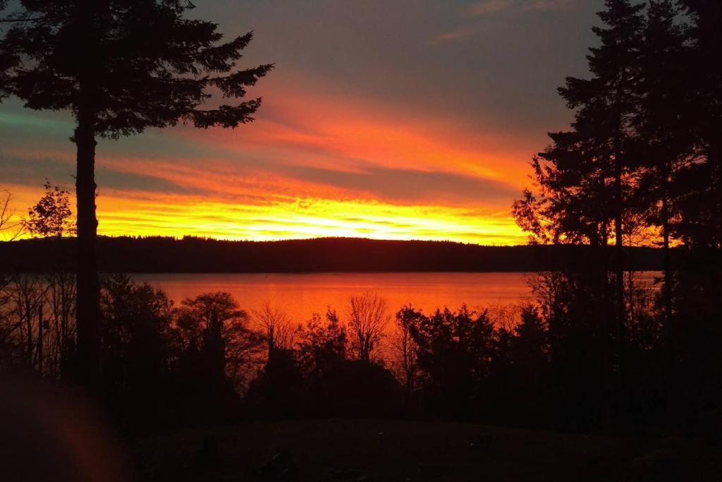 a sunset over a body of water with trees at Sunrise Suite on the Sound in Anacortes