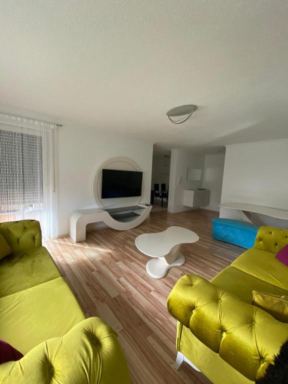 a living room with a yellow couch and a television at O&V Apartment in Waldshut-Tiengen