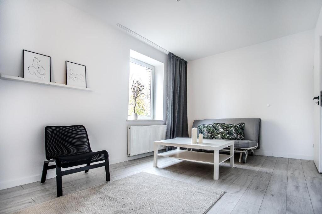 ein weißes Wohnzimmer mit einem Tisch und einem Stuhl in der Unterkunft Apartament Nadbystrzycka no. 02 in Lublin
