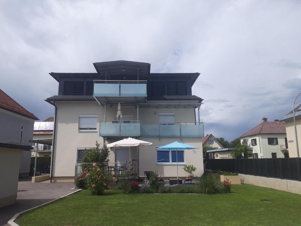 une maison avec une terrasse et un parasol dans une cour dans l'établissement Apartment and more, à Klagenfurt am Wörthersee