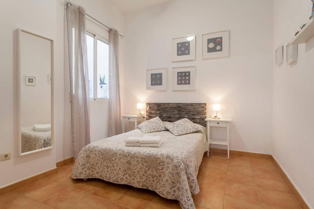 a white bedroom with a bed and a mirror at Puerto Bello in Valencia