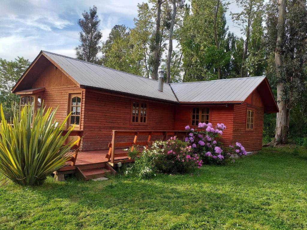 Cabaña de madera pequeña con porche y flores en Villa Rosa House, en Pinto