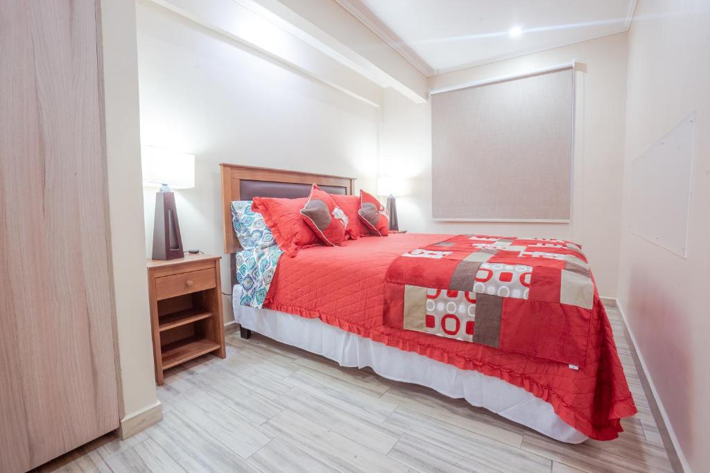 a bedroom with a bed with a red comforter at Santiago Rent Apart in Santiago