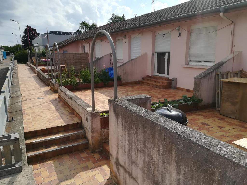 a house with a concrete retaining wall and a patio at Logement de plein pied à MIRECOURT in Mirecourt