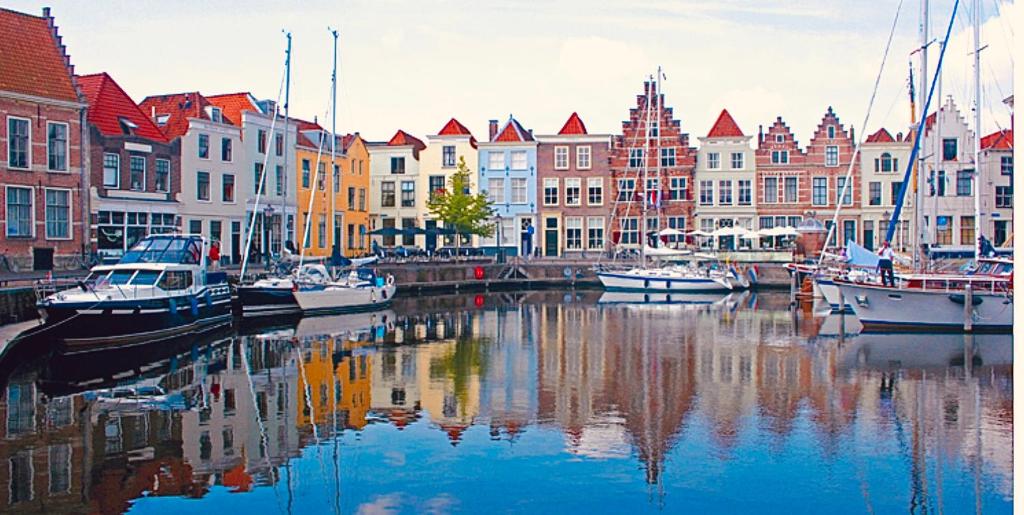 um grupo de barcos ancorados num canal com edifícios em HARBOR HOUSE ZEELAND - nl em Goes