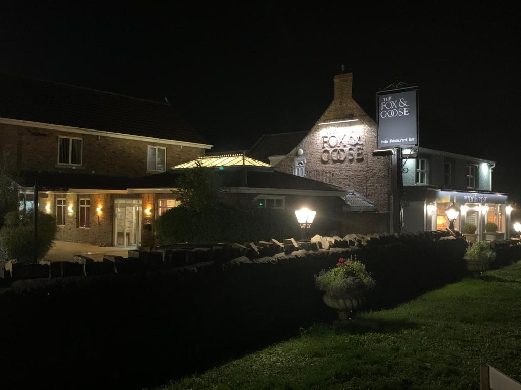 a building with a sign on the side of it at night at Fox and Goose Inn in Brent Knoll