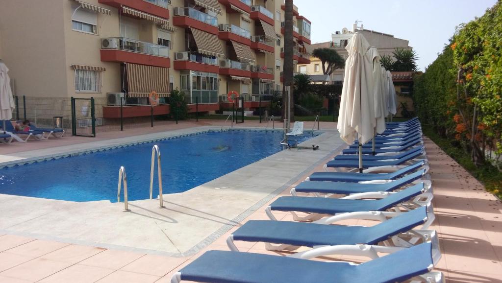 a row of lounge chairs next to a swimming pool at Apartamento Las Palomas Beach 201 in Torremolinos