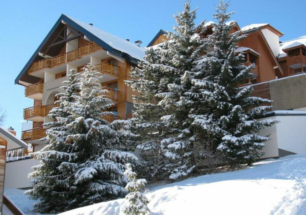 two snow covered pine trees in front of a building at Studio les deux alpes Résidence le Pluton B84 WIFI in Les Deux Alpes
