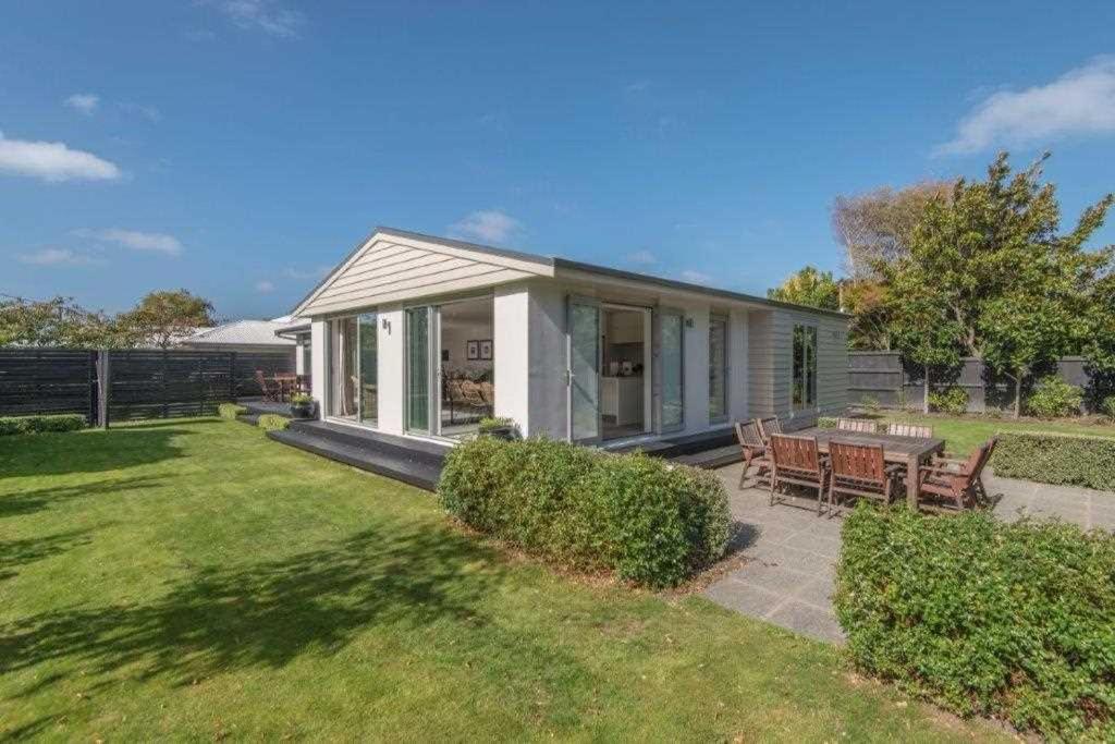 a small white house with a picnic table in a yard at Bed & Breakfast in the Heart of Fendalton in Christchurch