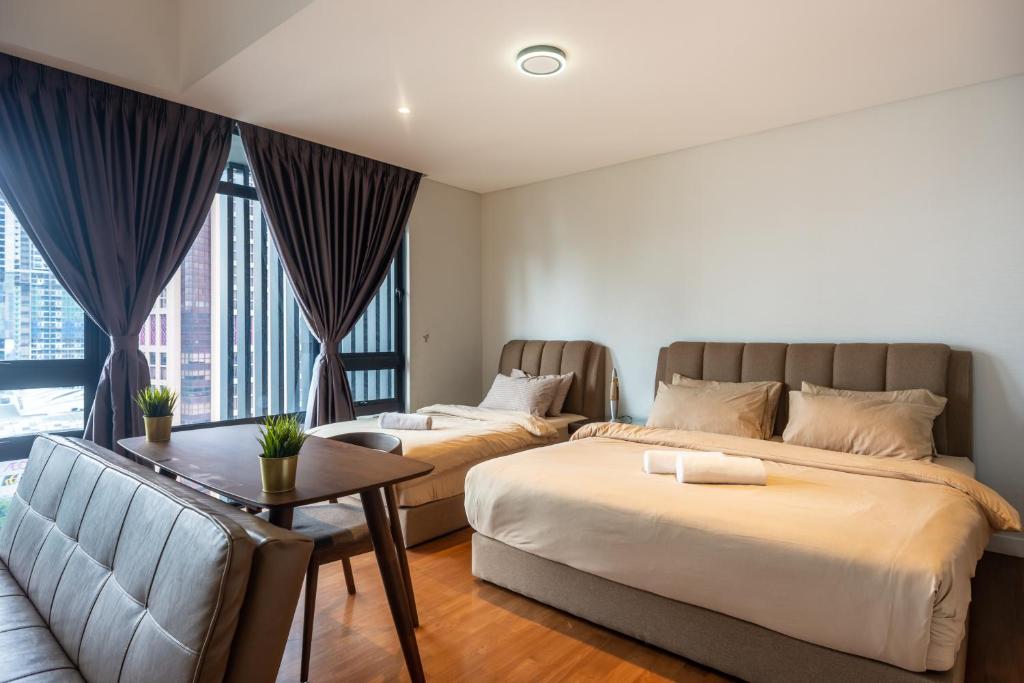 a bedroom with two beds and a table and a couch at Anggun Residences Luxe in Kuala Lumpur