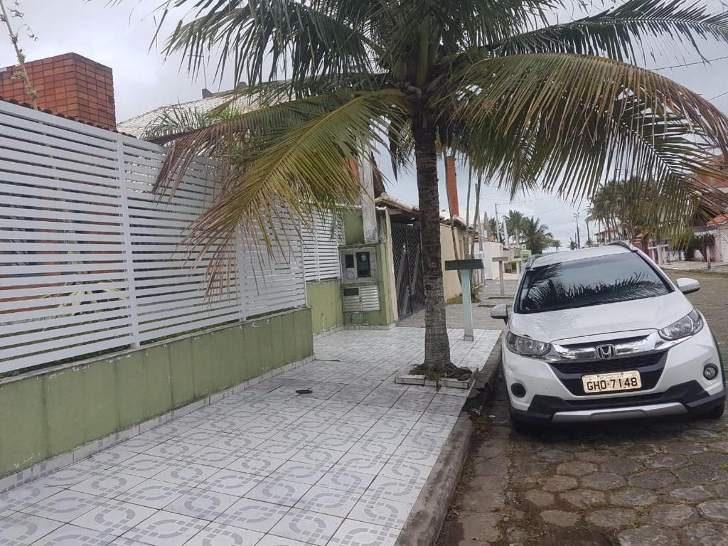 een witte auto geparkeerd naast een palmboom bij Casa aBeira Mar 200 metros da praia Peruíbe in Peruíbe