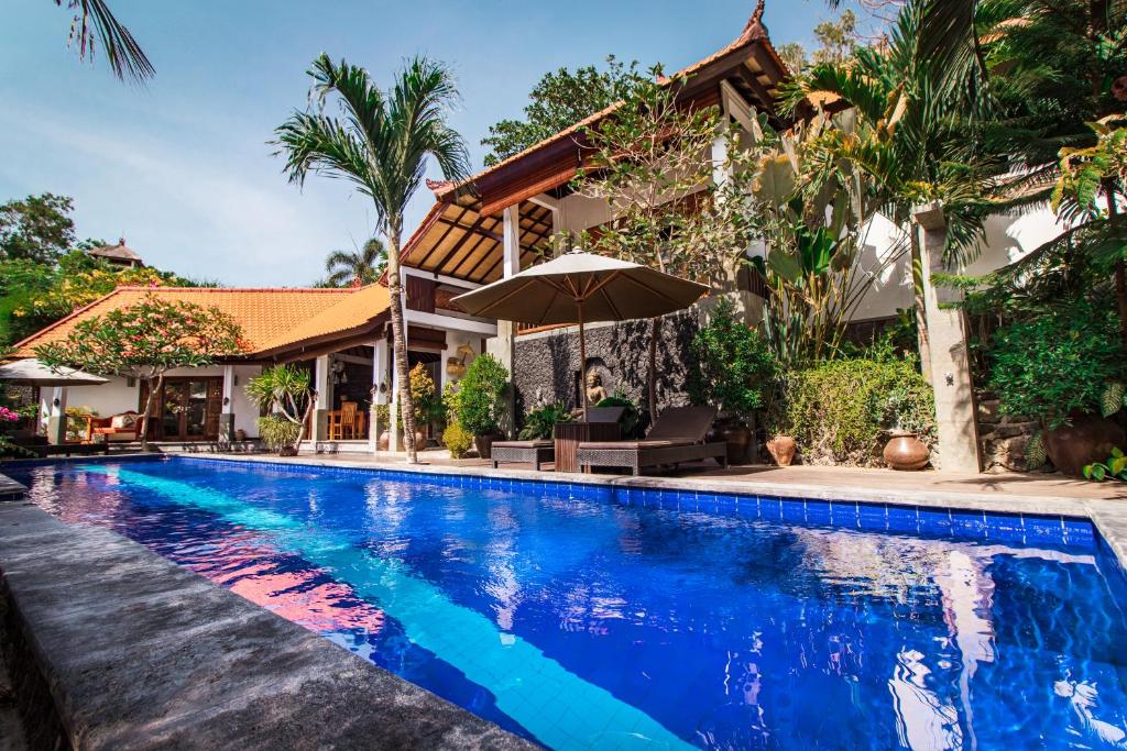 een zwembad voor een huis met een parasol bij Villa Bukit Malas 2 in Amed