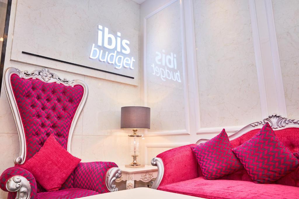 a living room with a red couch with pink pillows at ibis budget Singapore Joo Chiat in Singapore