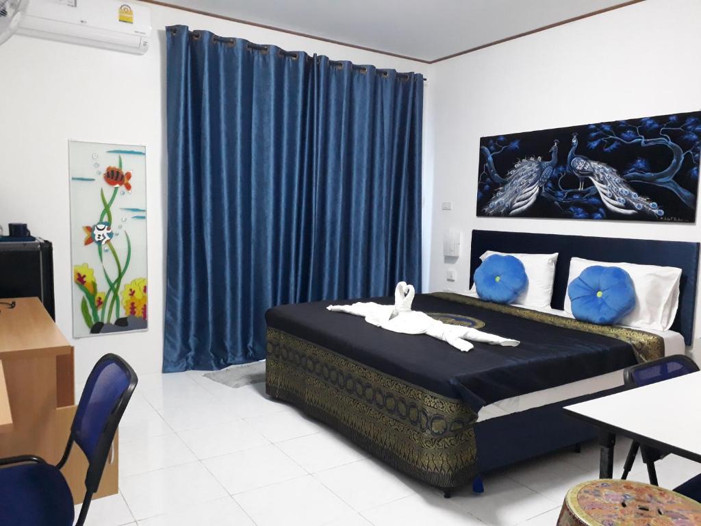 a bedroom with a bed and blue curtains at B&B NAMO PHUKET in Kathu