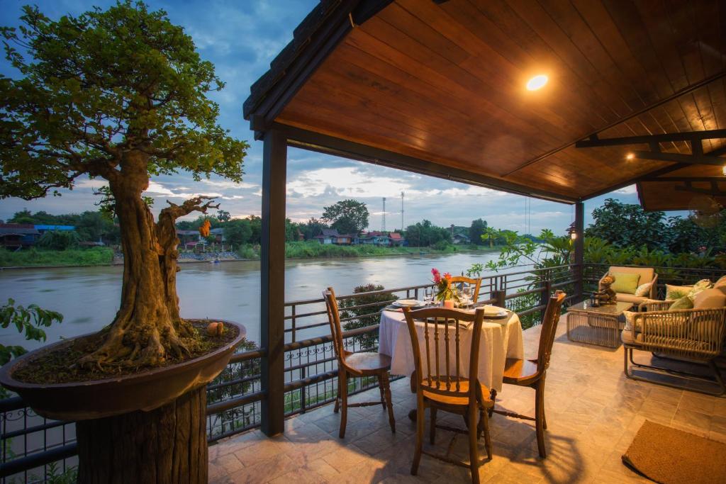 een tafel en stoelen op een veranda met een boom bij Cattani's Riverside Home in Phra Nakhon Si Ayutthaya