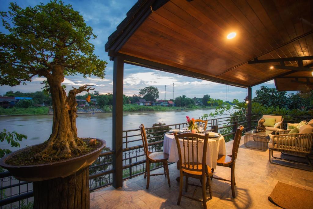 a table and chairs on a porch with a tree at Cattani's Riverside Home in Phra Nakhon Si Ayutthaya