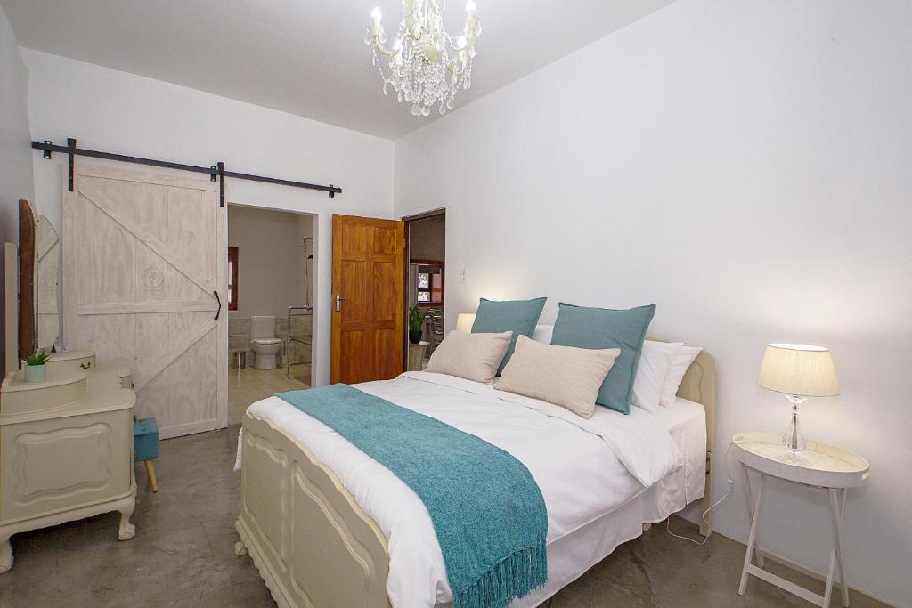 sypialnia z dużym łóżkiem i żyrandolem w obiekcie Merino Stal Guest Farm w mieście Ermelo