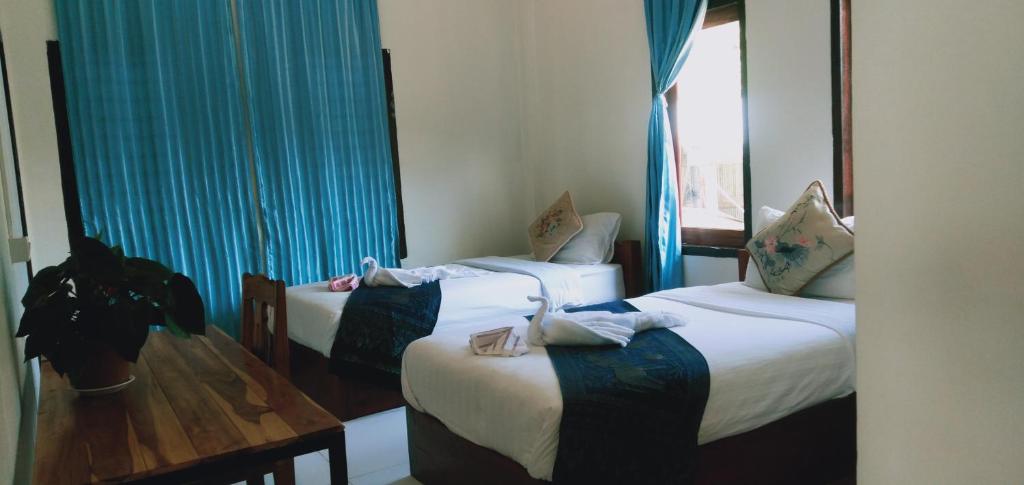 パークベンにあるVilla Mekong Guesthouseのブルーカーテン付きのホテルルーム内のベッド2台