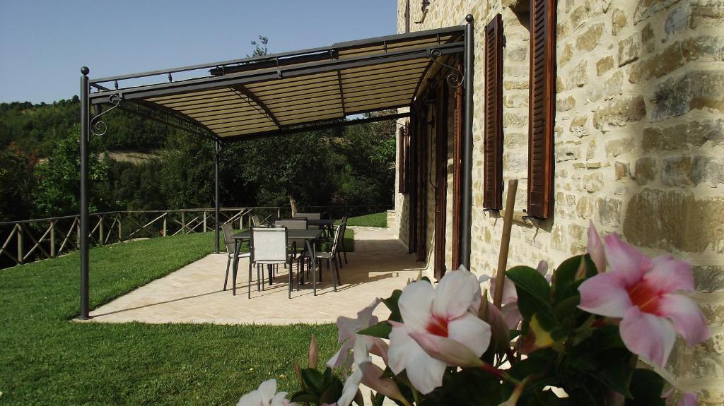 a patio with tables and chairs under a wooden pergola at Agriturismo Paradiso 44 in Assisi