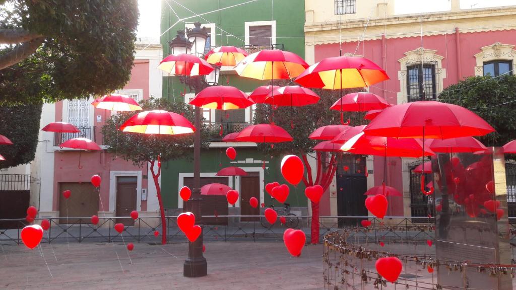 um monte de guarda-chuvas vermelhos em frente a um edifício em La Pita Guesthouse em Almeria