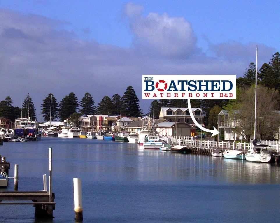 a marina with boats in the water and a sign at the boatshed waterfront b&b in Port Fairy