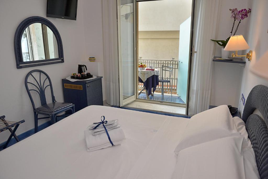 Cette chambre comprend une table blanche et un miroir. dans l'établissement Hotel Pensione Reale, à Maiori