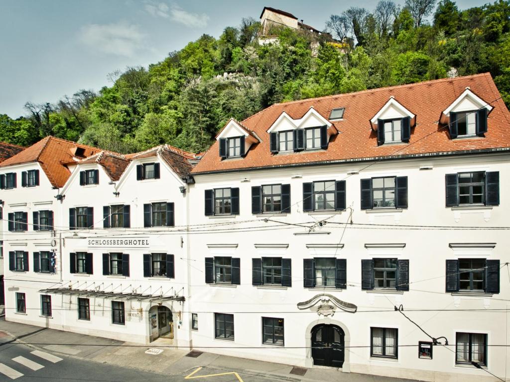 a large white building with a red roof at Schlossberghotel - Das Kunsthotel in Graz
