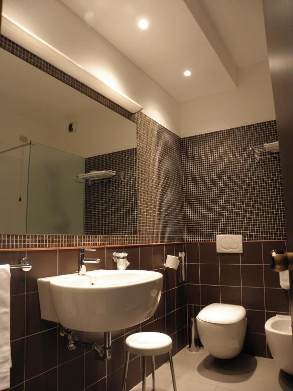 un bagno con lavandino, water e specchio di Hotel Ghironi a La Spezia