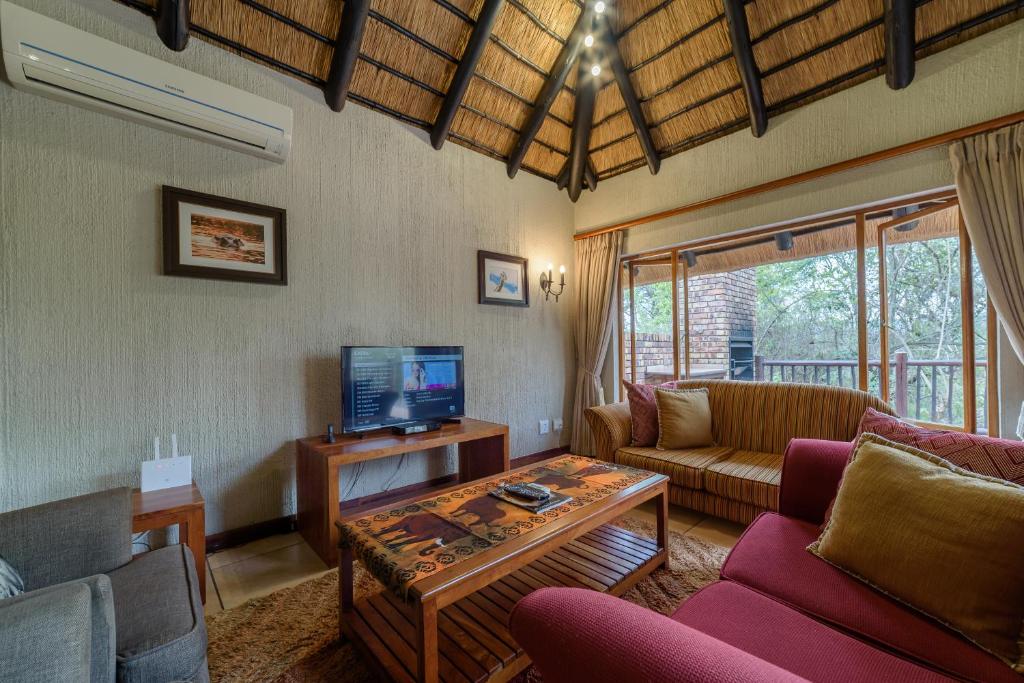 a living room with a couch and a tv at Kruger Park Lodge Unit No. 524 in Hazyview