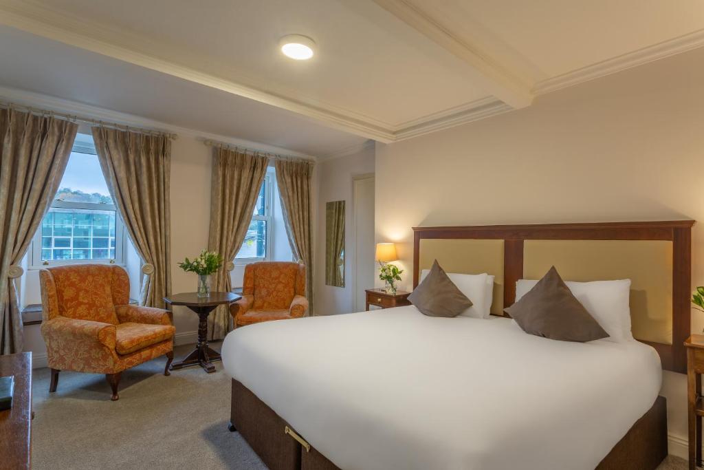 a hotel room with a large bed and chairs at Dooley's Hotel in Waterford