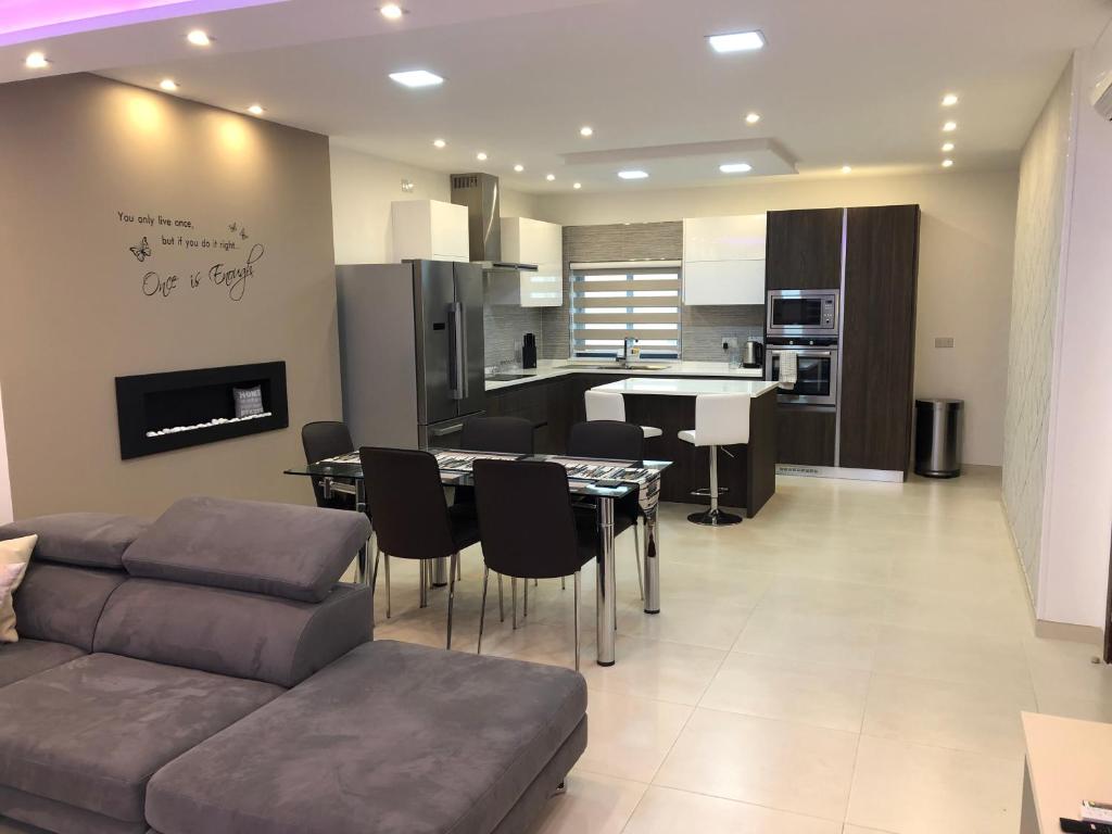 een woonkamer en een keuken met een bank en een tafel bij Relax Zabbar in Żabbar