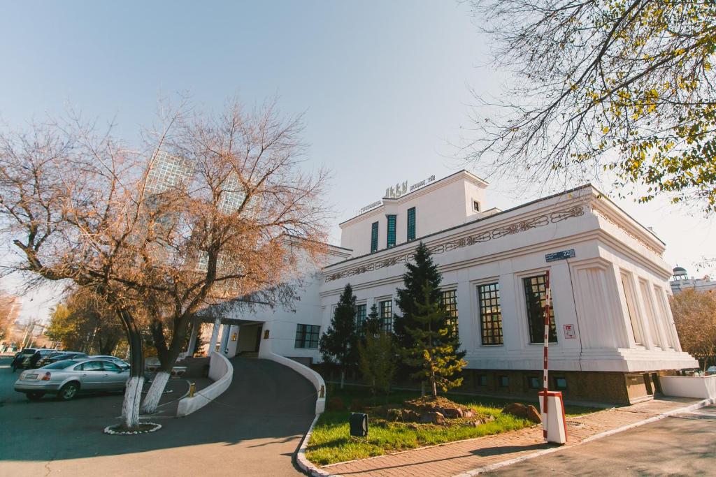 Un bâtiment blanc avec une voiture garée devant. dans l'établissement Акку, à Astana