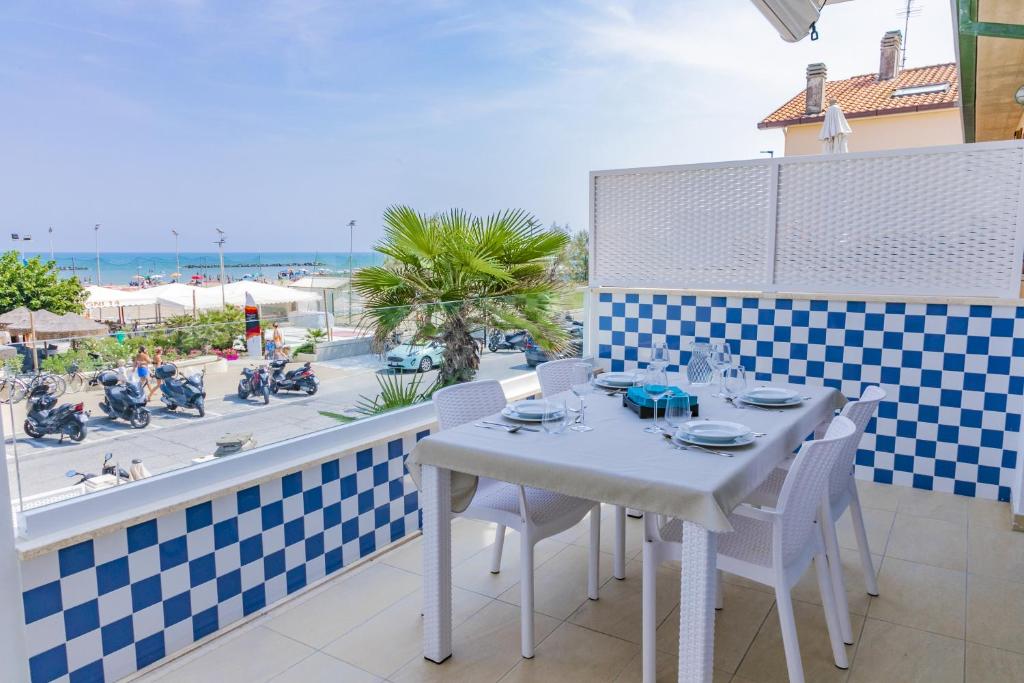 d'une table et de chaises blanches sur un balcon avec vue sur la plage. dans l'établissement CASA E MARE, à Senigallia