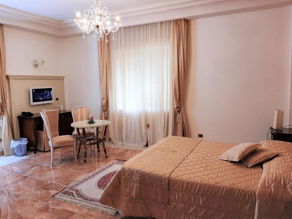 una camera con letto, tavolo e lampadario a braccio di Regina di Saba - Hotel Villa per ricevimenti a Grottaminarda