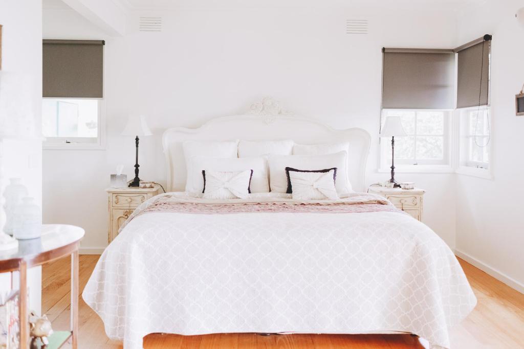 een witte slaapkamer met een wit bed en 2 nachtkastjes bij Dalblair Bed & Breakfast in Seville