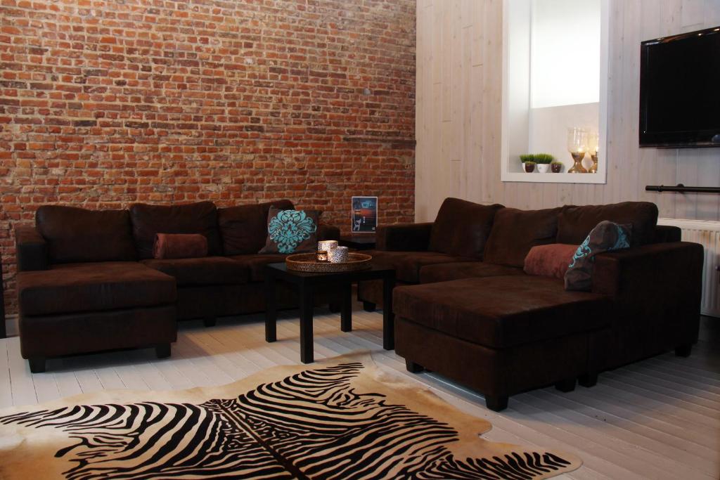 una sala de estar con 2 sofás y una pared de ladrillo en B&B Casa Luna Loft en Dendermonde