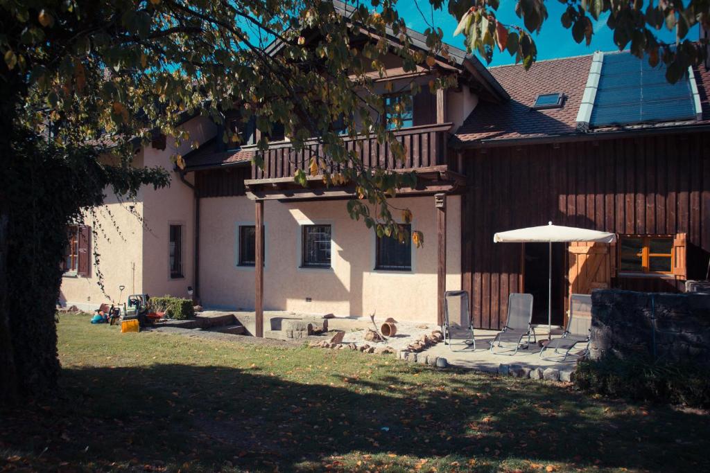 une terrasse avec des chaises et un parasol en face d'une maison dans l'établissement Ferienwohnung zum Forsthaus, à Oberviechtach