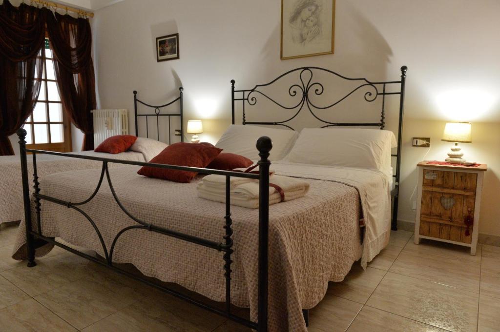 um quarto com uma cama com lençóis brancos e almofadas vermelhas em Dimora Carmine em Alberobello