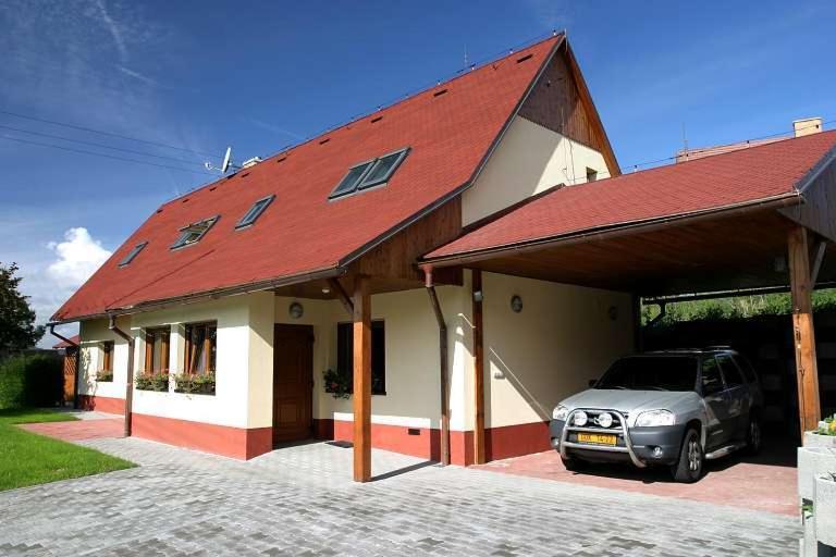 a car parked outside of a house with a red roof at Chalupa Bella in Žamberk