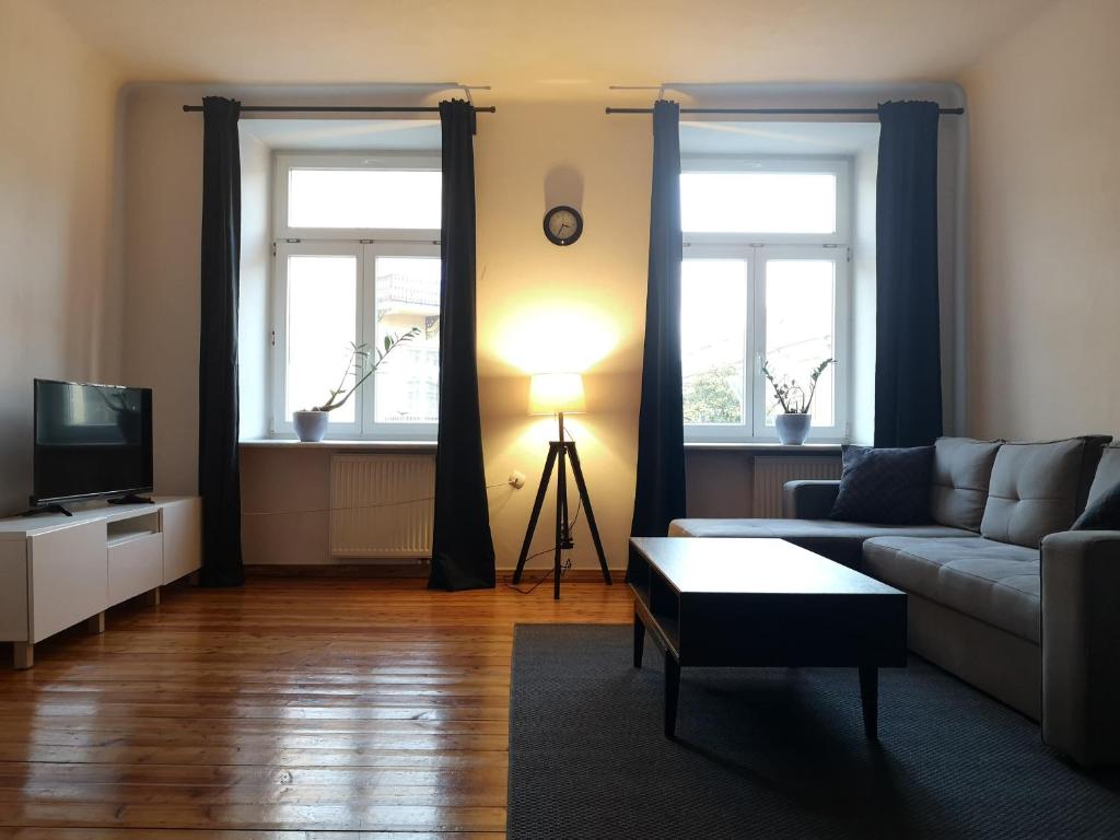een woonkamer met een bank en 2 ramen bij Apartamenty Krakowskie 36 Lublin - Double One in Lublin