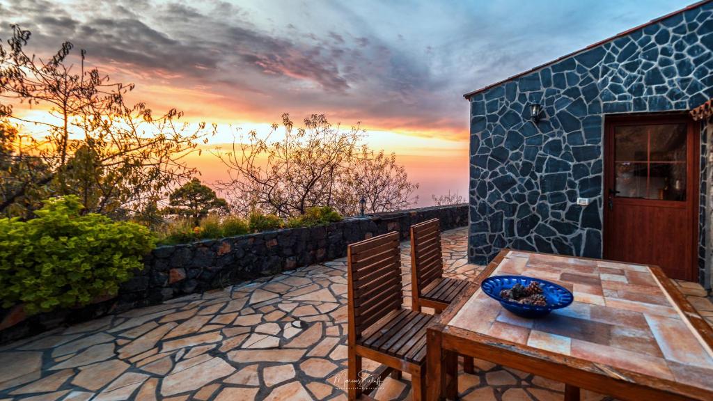 stół i krzesła na patio z widokiem na zachód słońca w obiekcie sunset and stars stone house w mieście Garafía