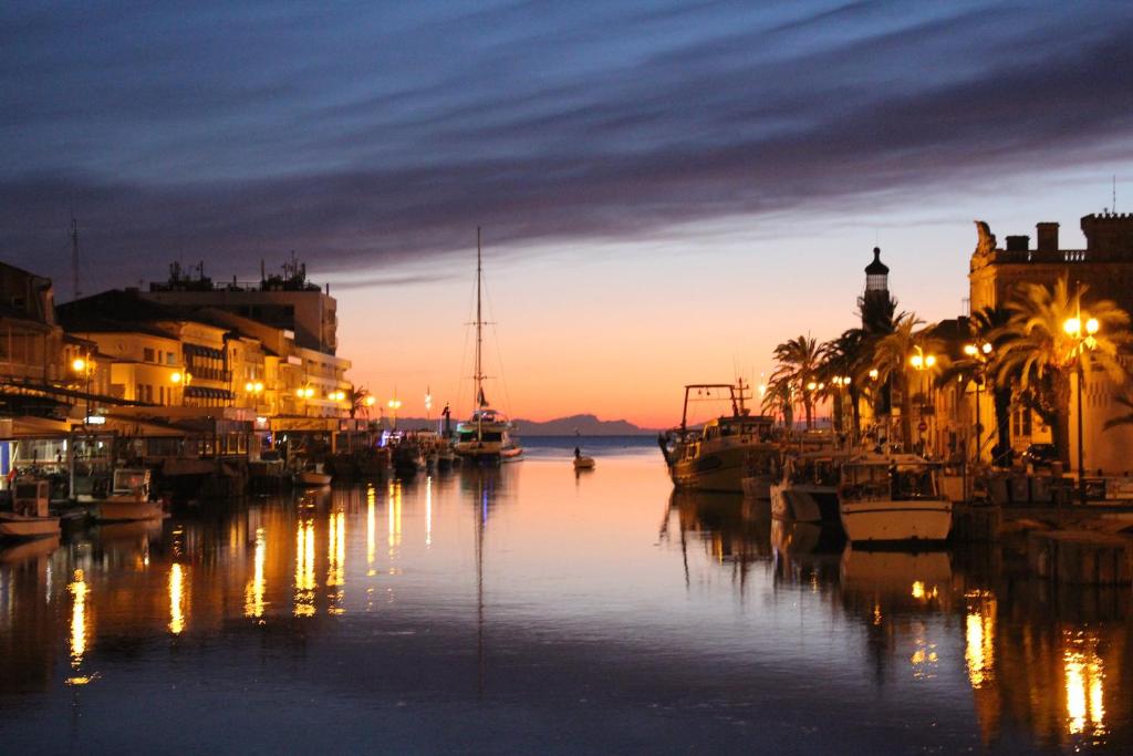 a canal with buildings and palm trees at night at Studio 237 Port Camargue, Piscine, Climatisation, 2 personnes in Le Grau-du-Roi