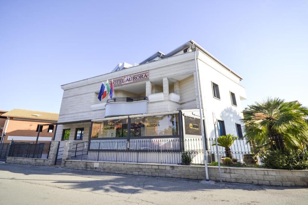 a white building with a fence in front of it at Hotel Aurora Wellness & SPA in Tivoli Terme