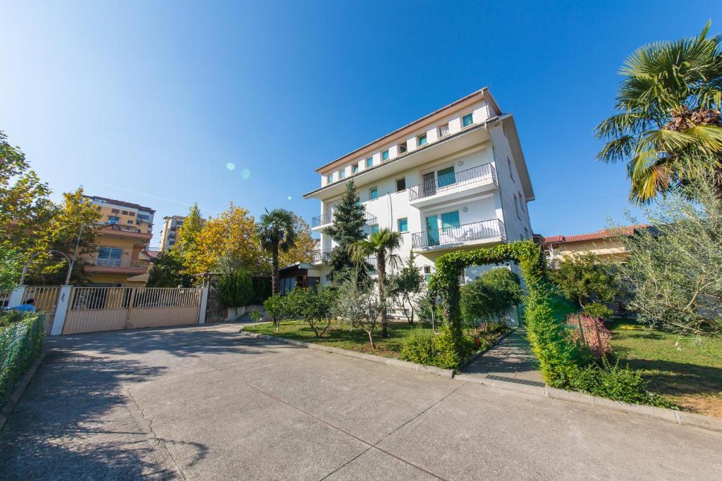 an apartment building on a sunny day with a driveway at Hotel Heritage in Tirana