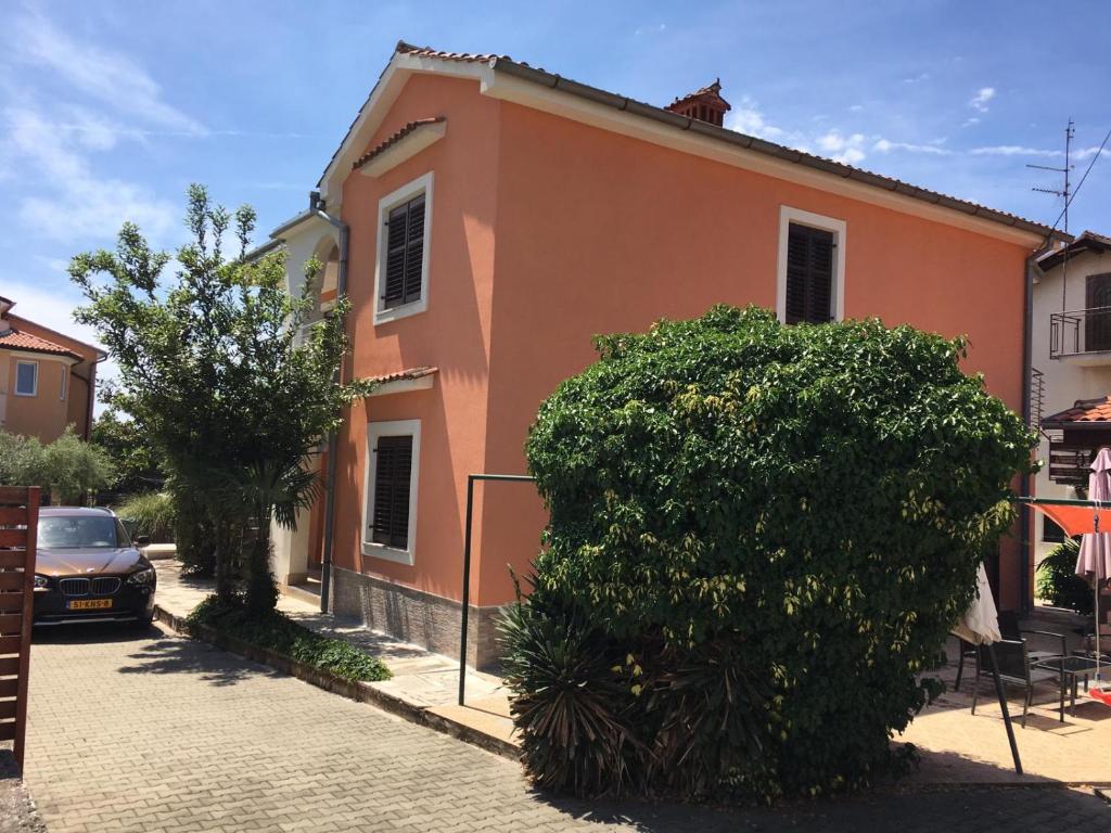 una casa arancione con un grande cespuglio di fronte di Apartment Luna met Airco Wifi en Zwembad a Novigrad Istria