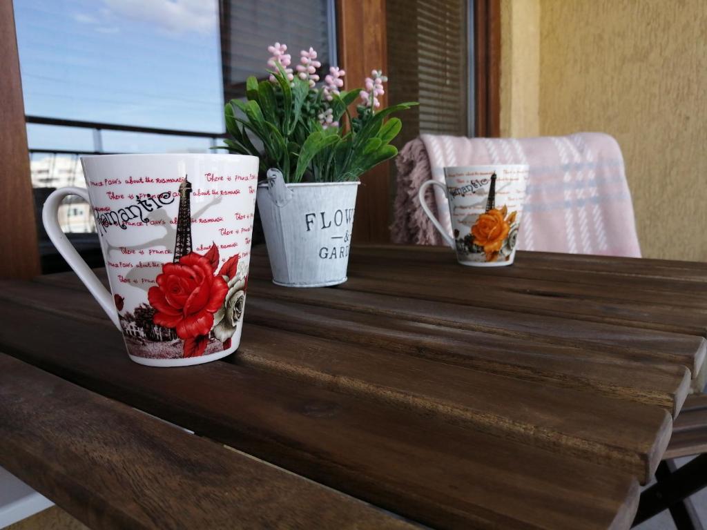 three coffee mugs sitting on a wooden table with flowers at INFINITY Blue 2 in Burgas