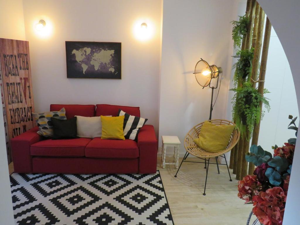 a living room with a red couch and a chair at Casa da Rita in Évora