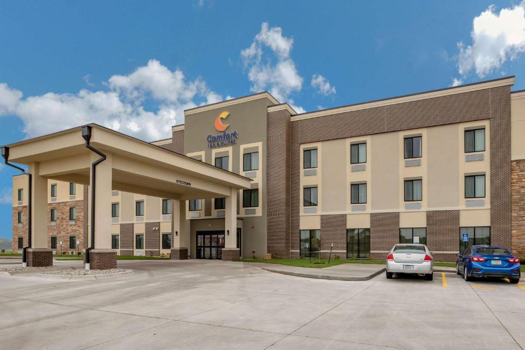 Comfort Inn and Suites Ames near ISU Campus في أيمز: مبنى مكتب فيه سيارات تقف في موقف للسيارات