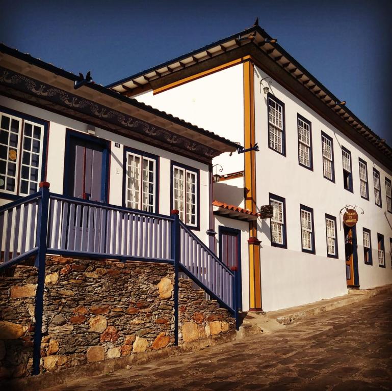 een wit gebouw met een blauw hek ernaast bij Pouso da Chica in Diamantina