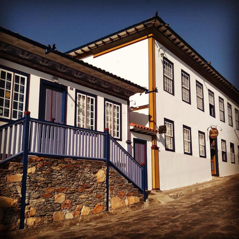 a white building with a blue fence next to it at Pouso da Chica in Diamantina